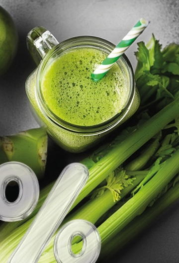 Green juice with celery and apple in a glass with a straw