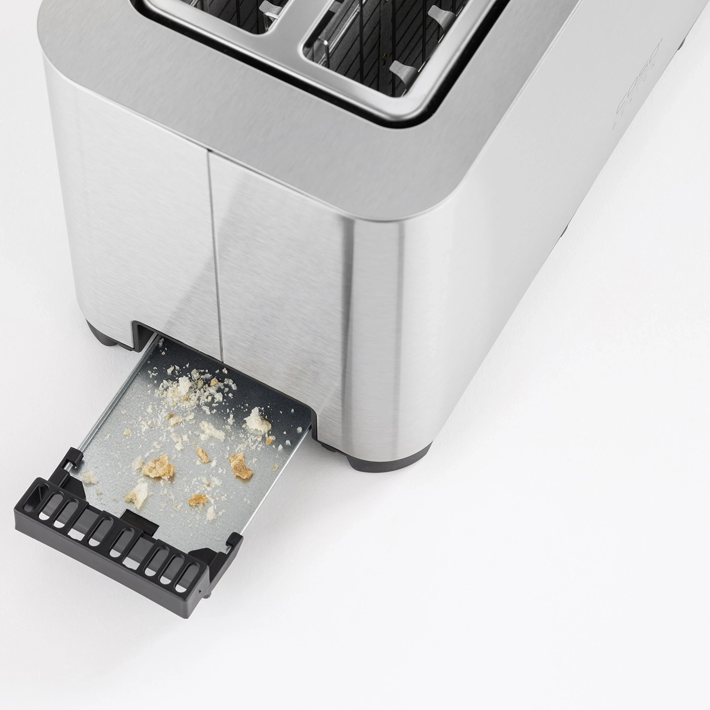 Toaster mit herausgezogener Krümelschublade und Brotkrümeln auf weißem Hintergrund.