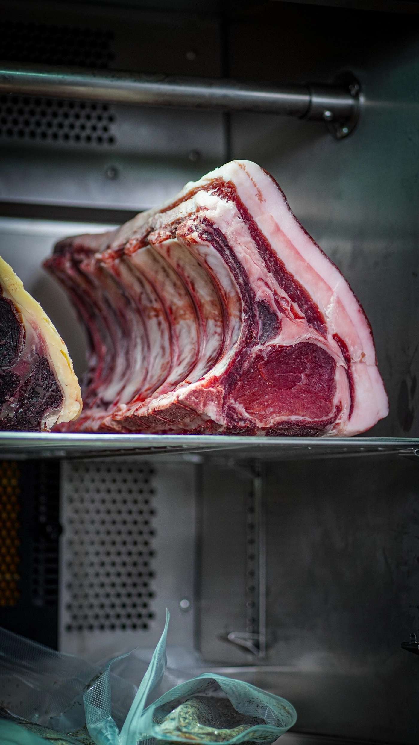 Raw beef rib roast with fat and bones in a refrigerator.