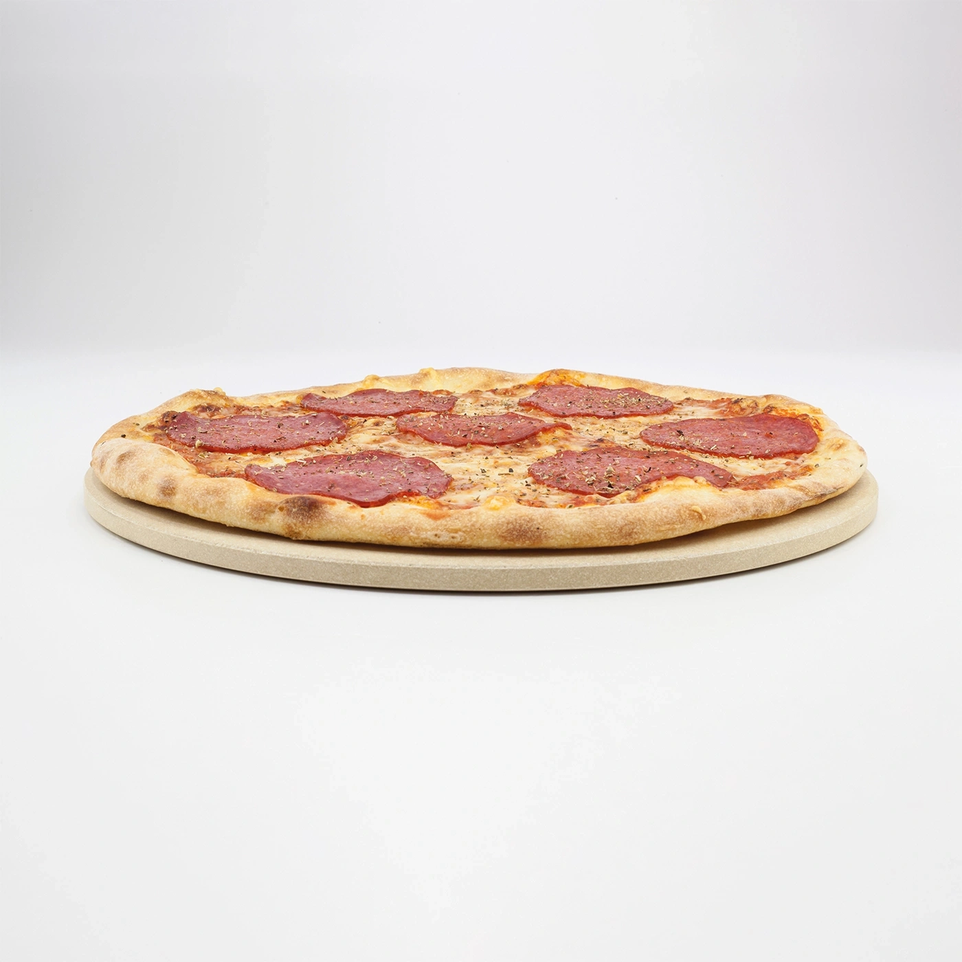 Pizza with salami on a pizza stone against a white background
