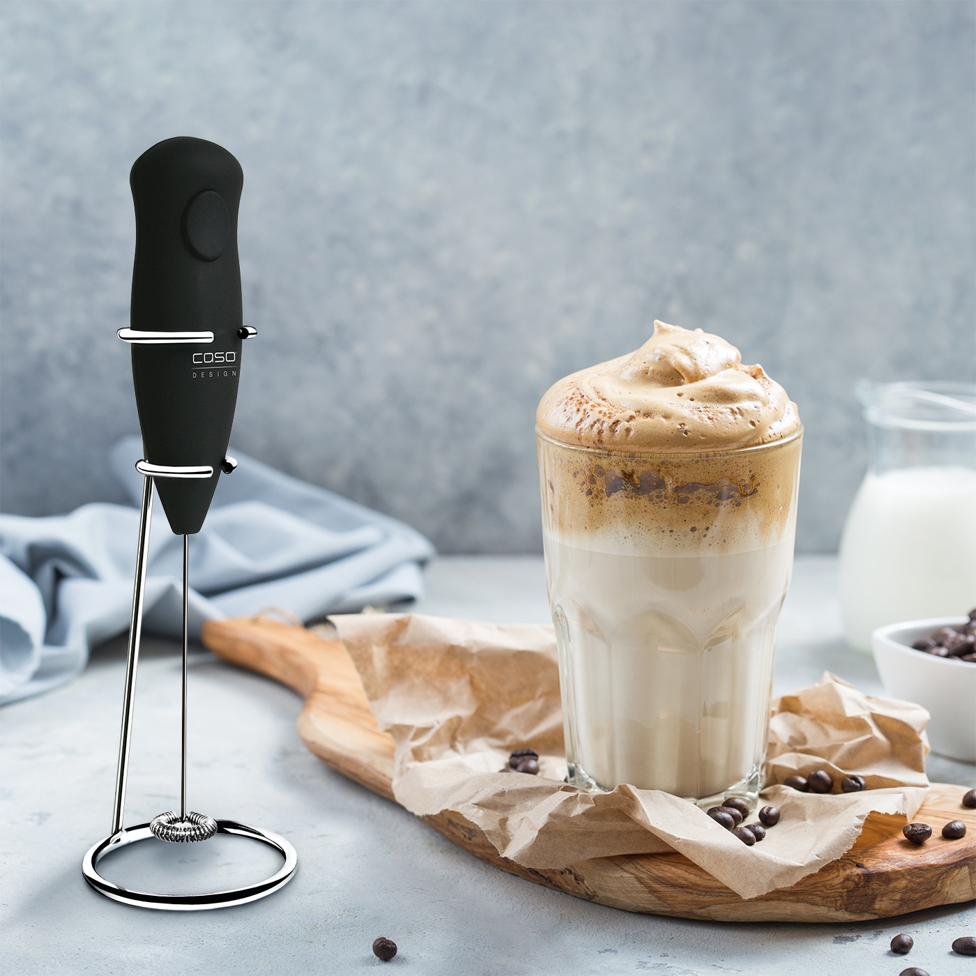 Coffee drink with milk and foam, next to a milk frother.