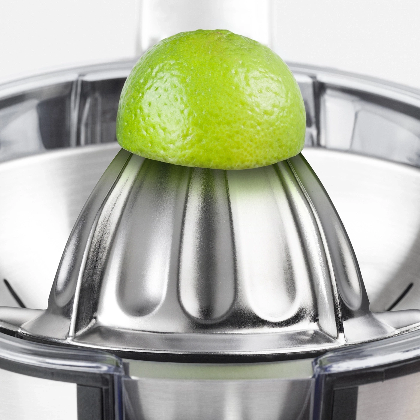 Eine Limette auf einer Zitruspresse. Nahaufnahme. Edelstahl. Grün.