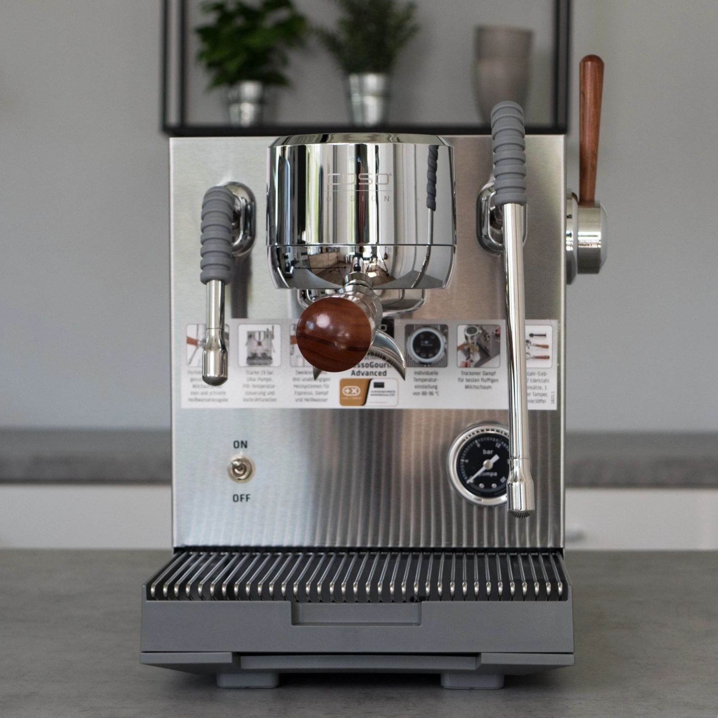 Eine glänzende Espressomaschine mit Holzgriff und Dampfrohr.