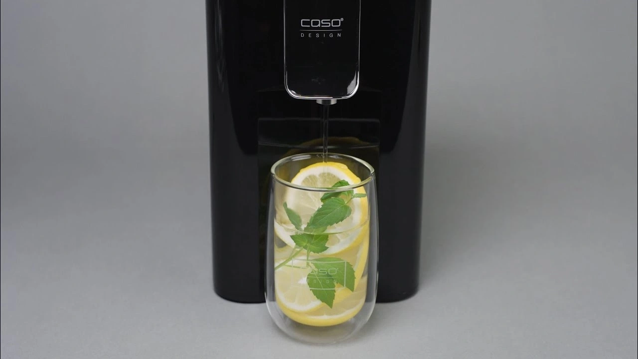 Black water dispenser with glass, lemon and mint, grey background