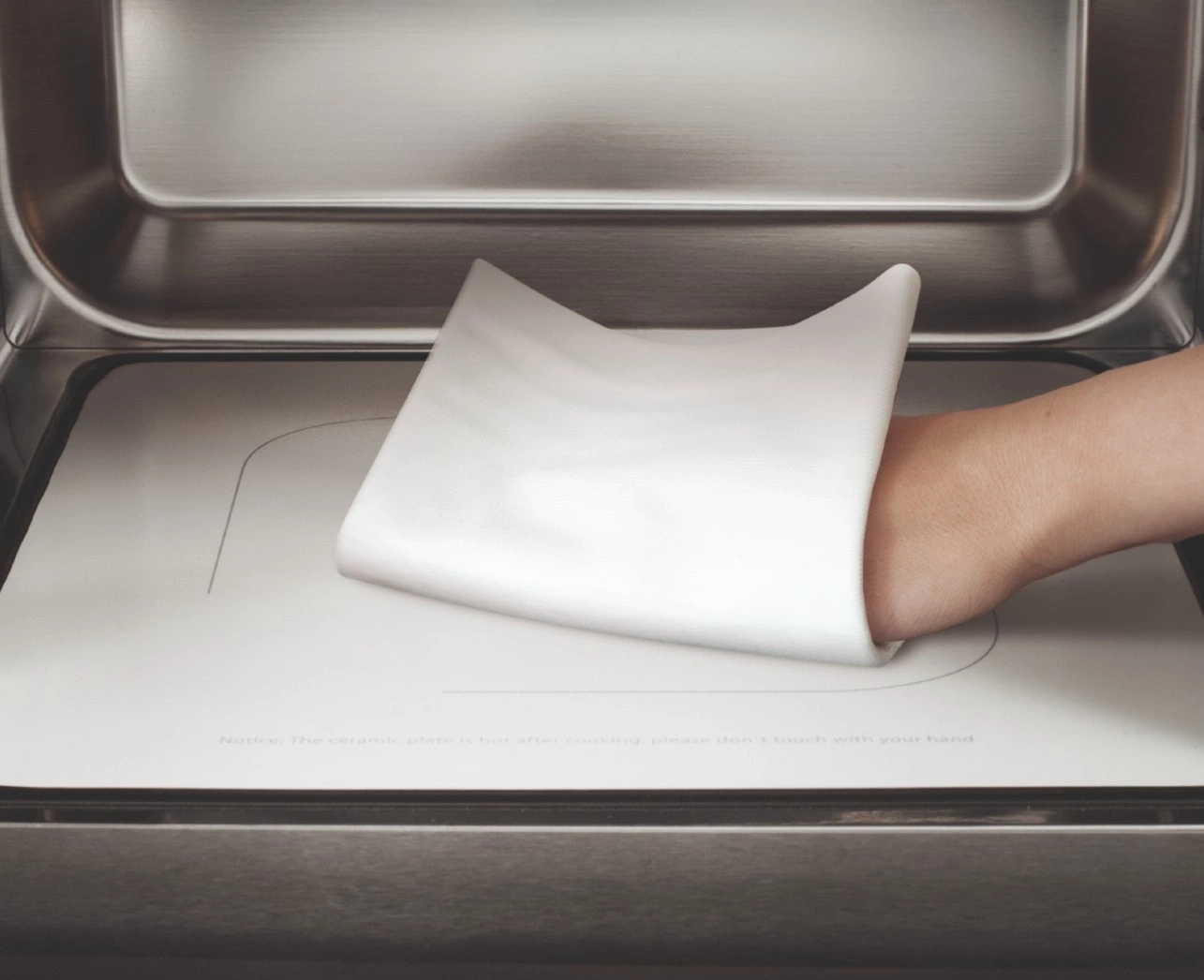 Hand berührt heiße Platte. Vorsicht, die Platte ist heiß! Nicht berühren!