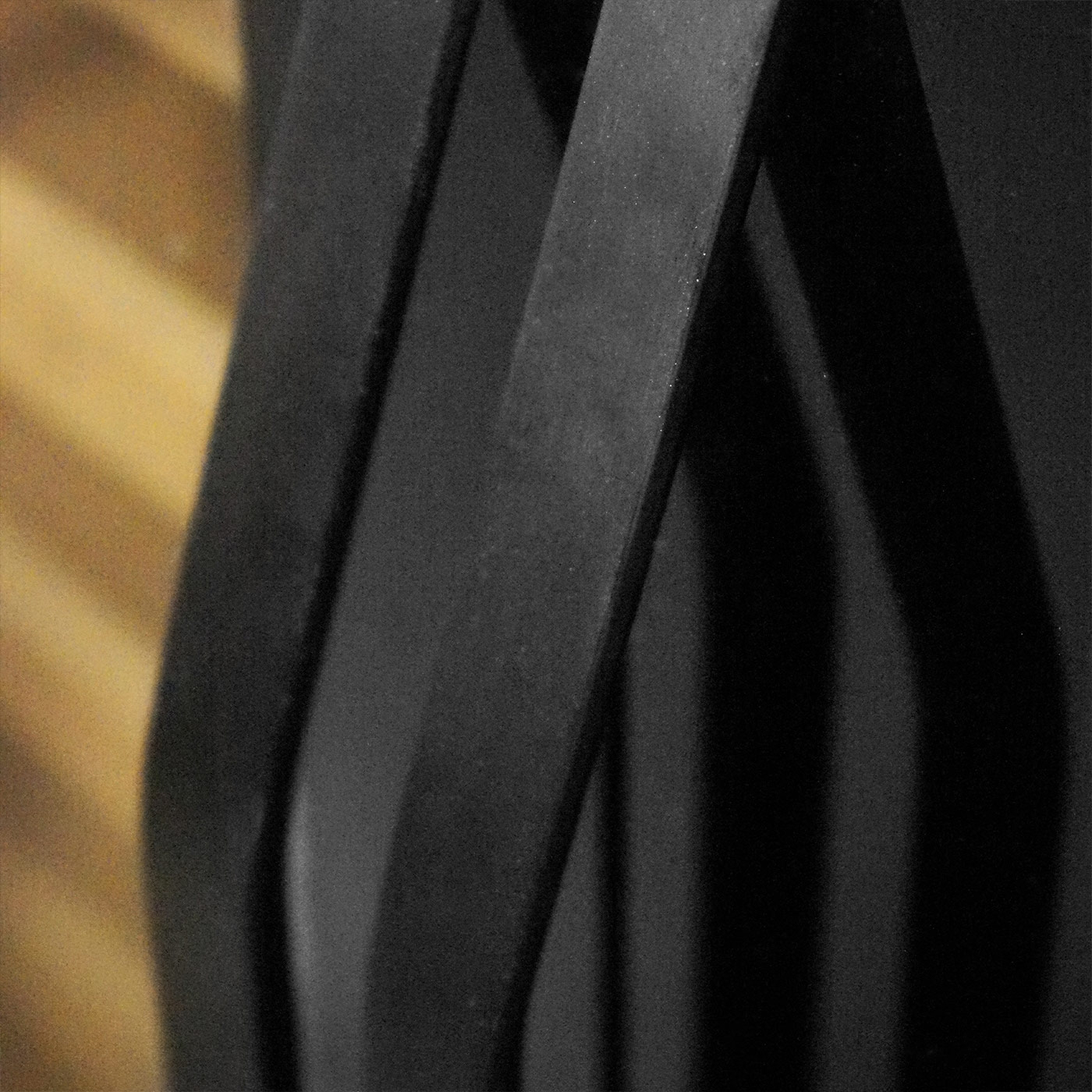 Close-up of black, curved metal strips with wood in the background