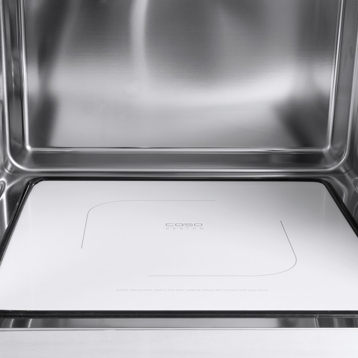 Inside of an oven with white plate and Caso logo, stainless steel