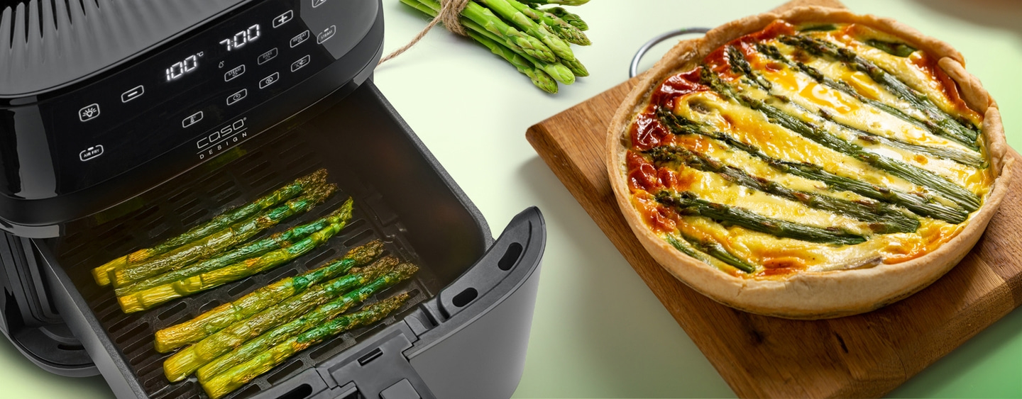 Air fryer with asparagus and quiche on wooden board, delicious food
