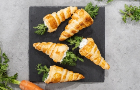 Delicious puff pastry horns with cream on a black board