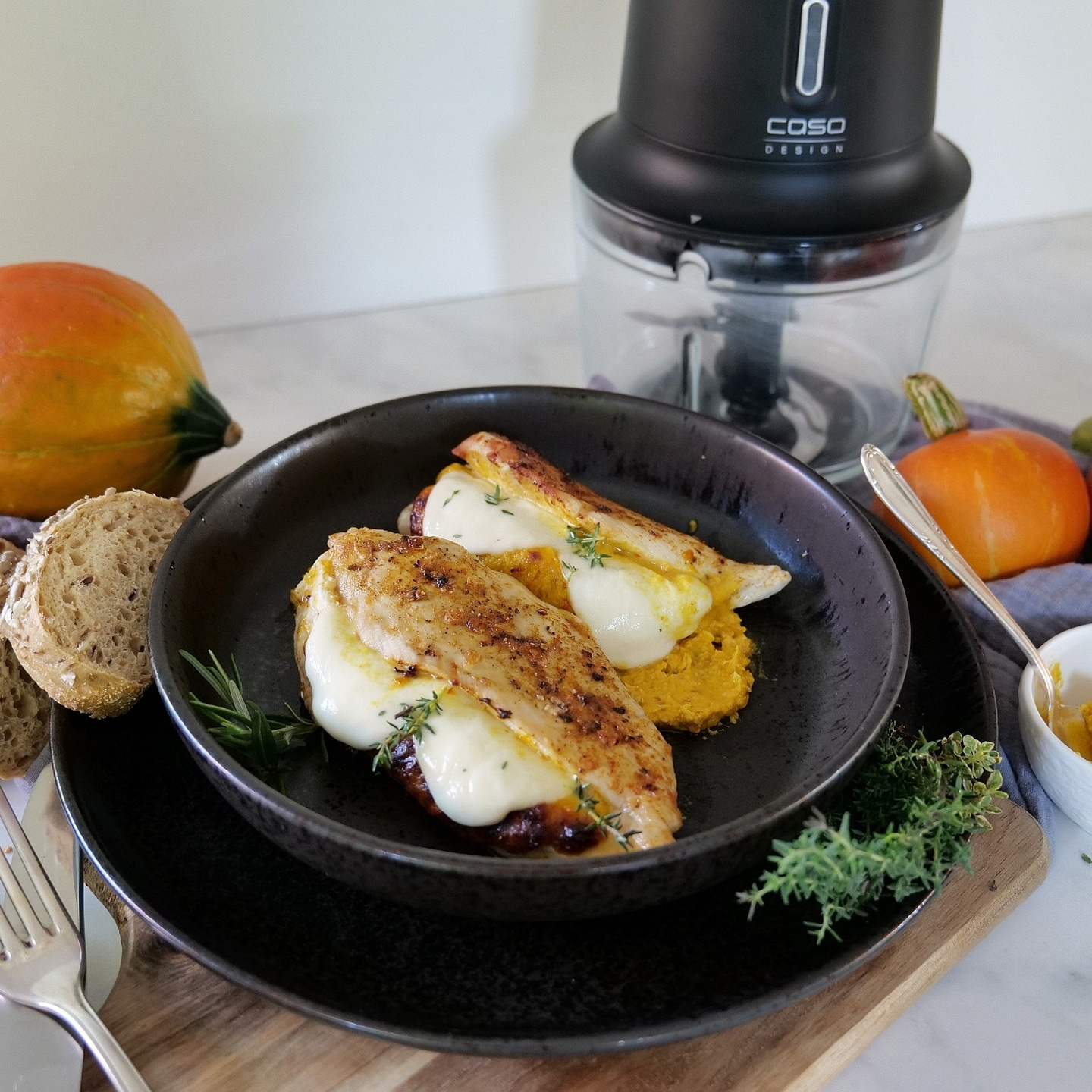 Chicken breast with cheese and pumpkin on a plate with bread and herbs