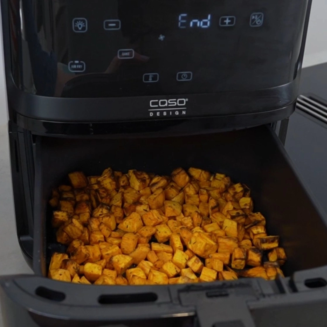 An air fryer with roasted sweet potato cubes and the word "End" on the display.