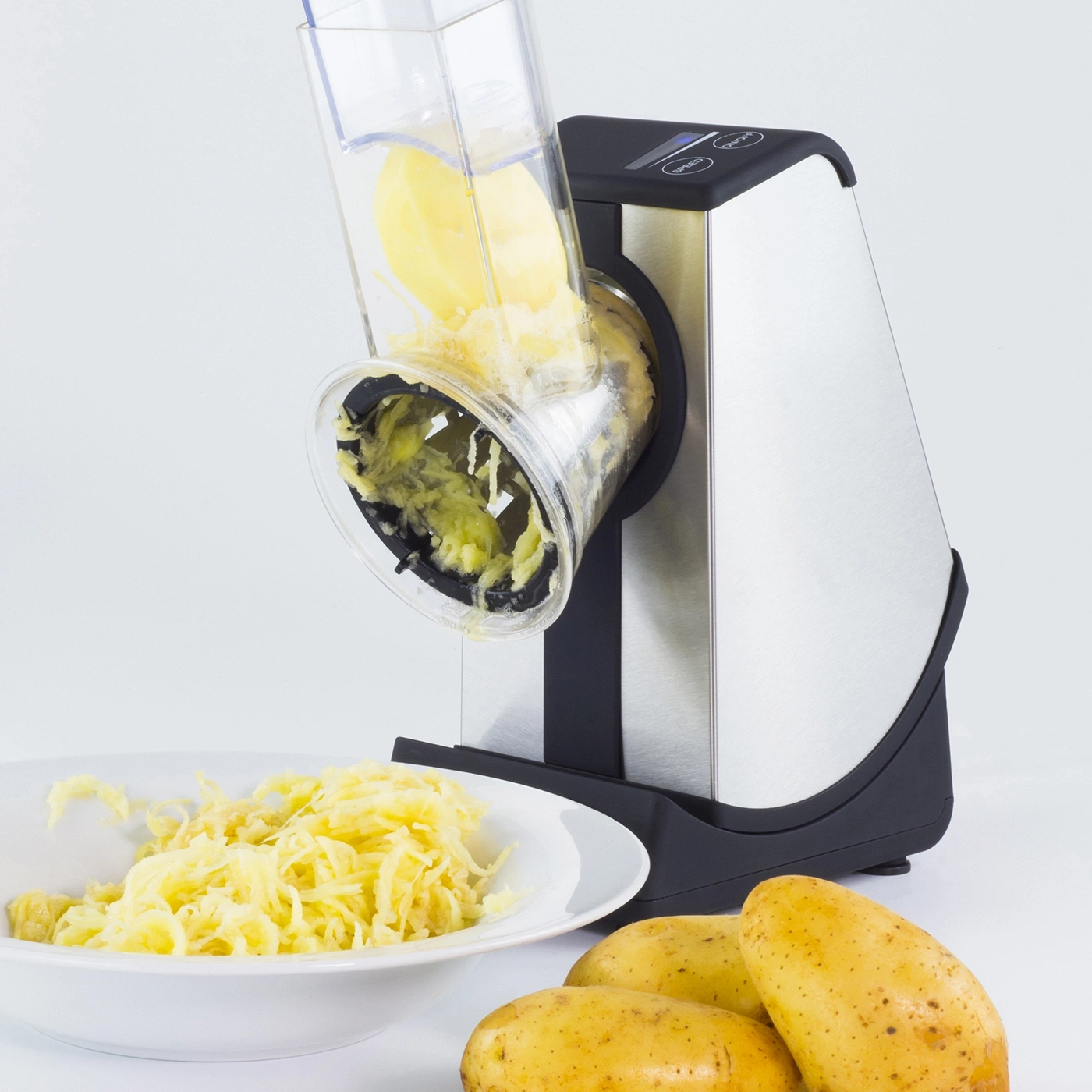 Potato grater with potatoes and grated potatoes in a bowl on white background