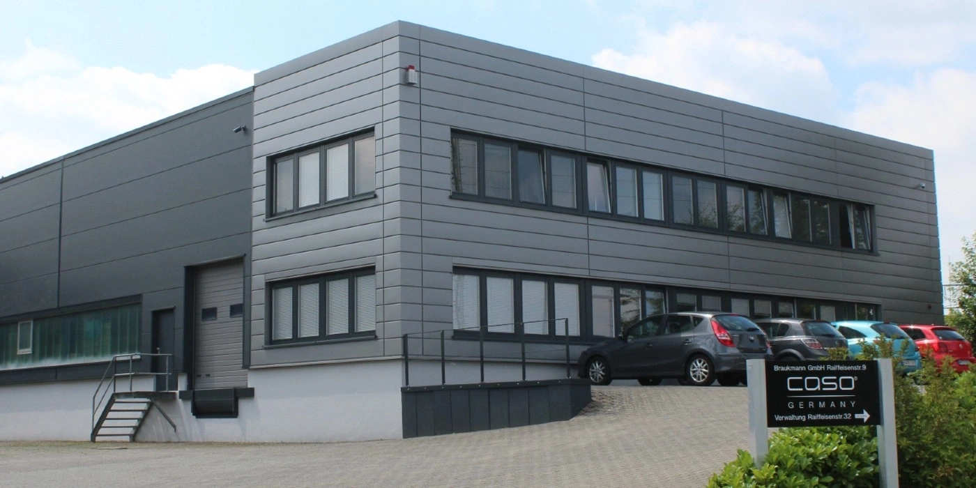 Gray building with cars and a sign in Germany. Modern architecture.