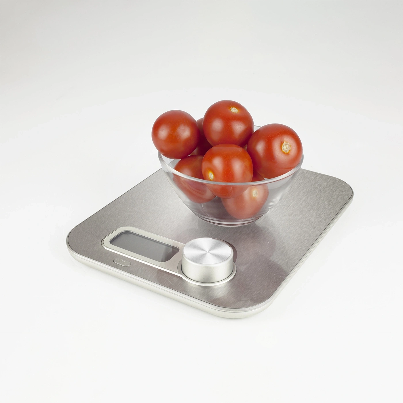 Tomatoes in a glass bowl on a kitchen scale. Weighing food ingredients.