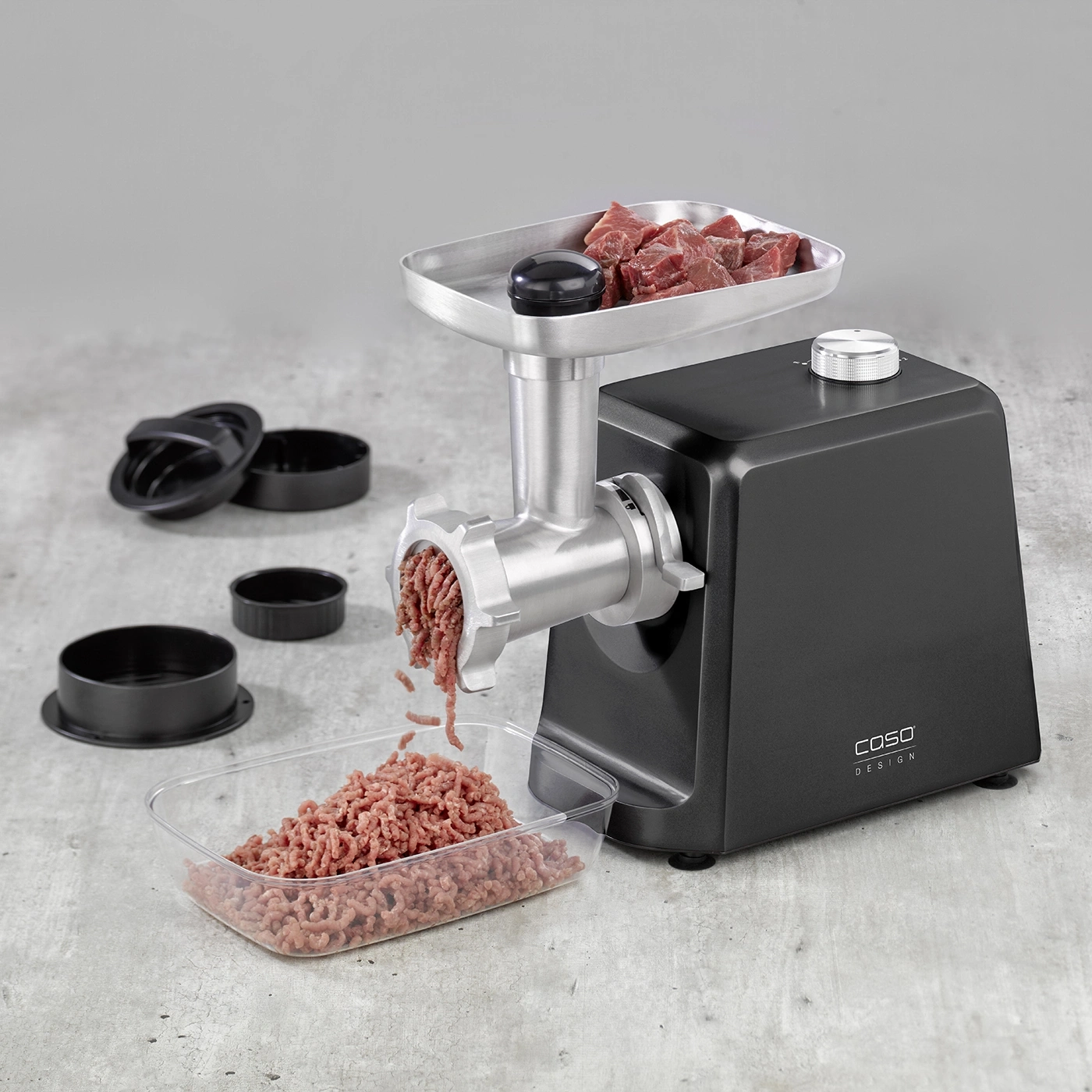 Meat grinder with meat and accessories on gray surface, close-up shot