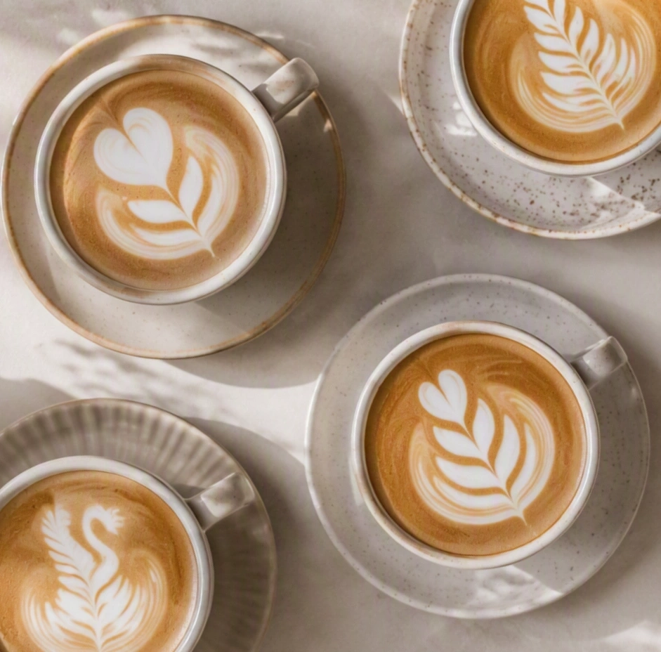 Four coffee drinks with latte art on a table