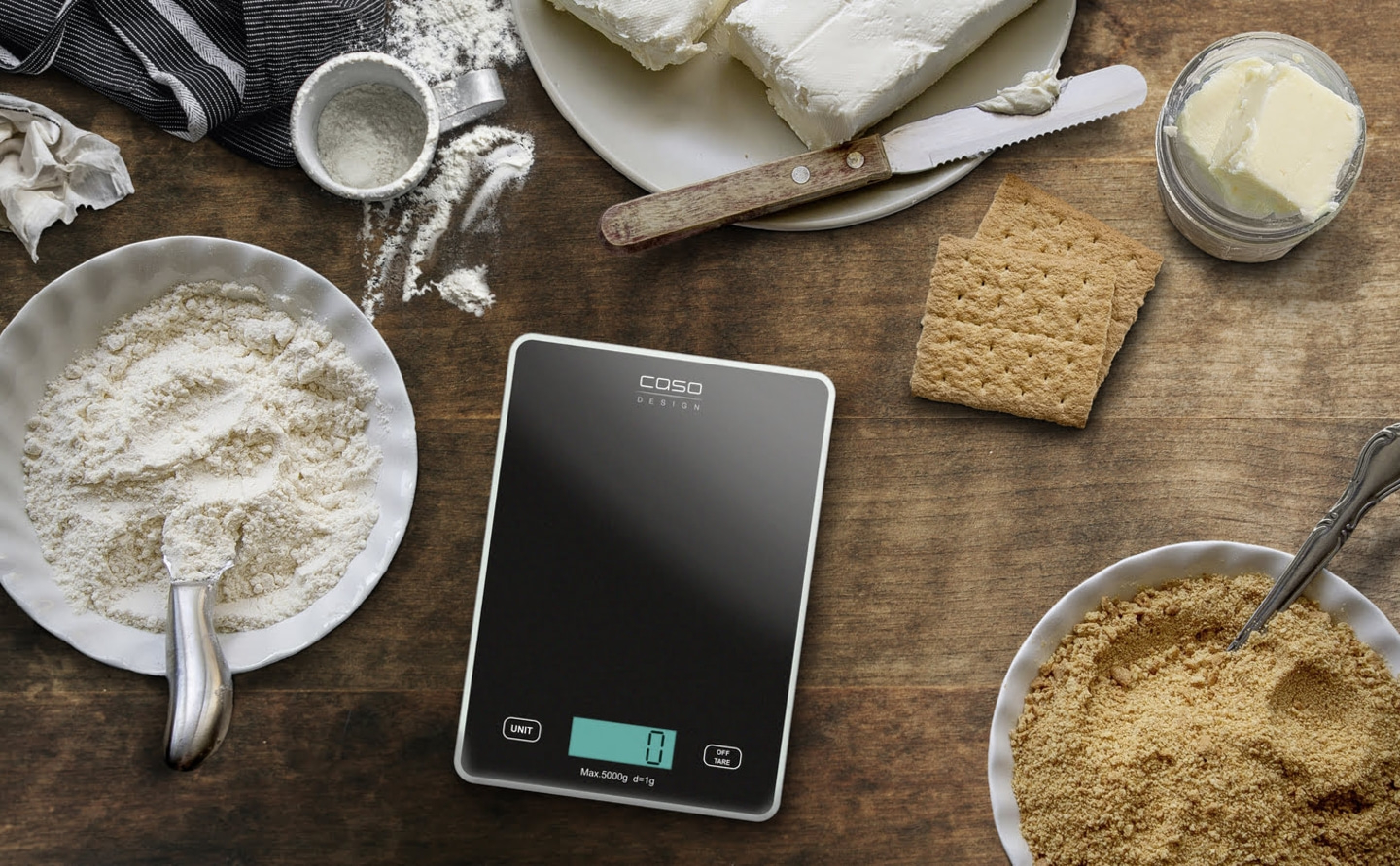 Küchenwaage mit Zutaten für einen Kuchen auf einem Holztisch
