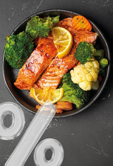 Grilled salmon fillet with broccoli, cauliflower, and carrots, garnished with lemon, with percentage signs next to it.