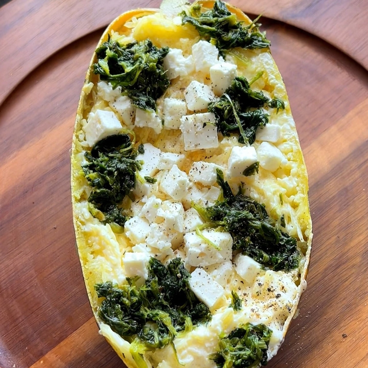 Stuffed squash with spinach and feta cheese on a wooden plate