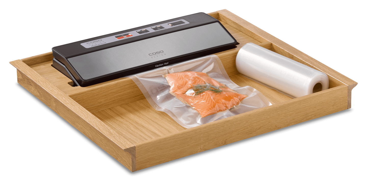 Ein Vakuumiergerät mit Lachs und Folienrolle in einer Holzschublade.