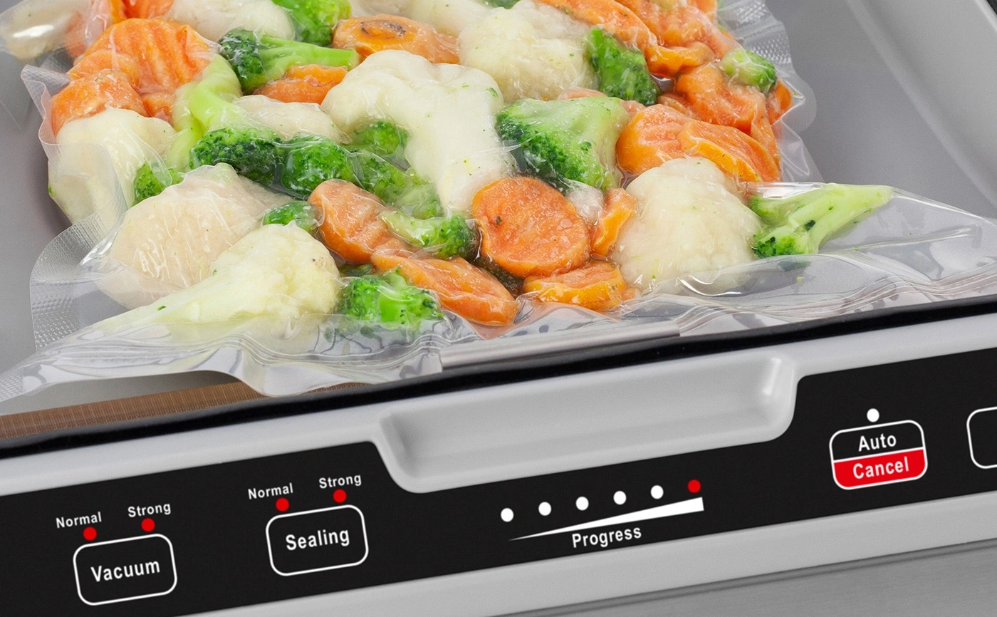 Vegetables in a vacuum sealer. Progress is shown. Vacuuming and sealing process is in progress.