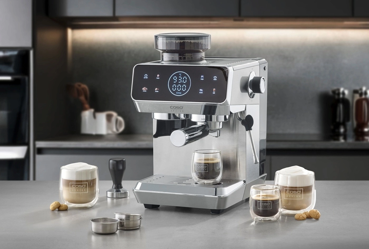 Eine silberne Espressomaschine mit digitalem Display und zwei Gläsern Kaffee.
