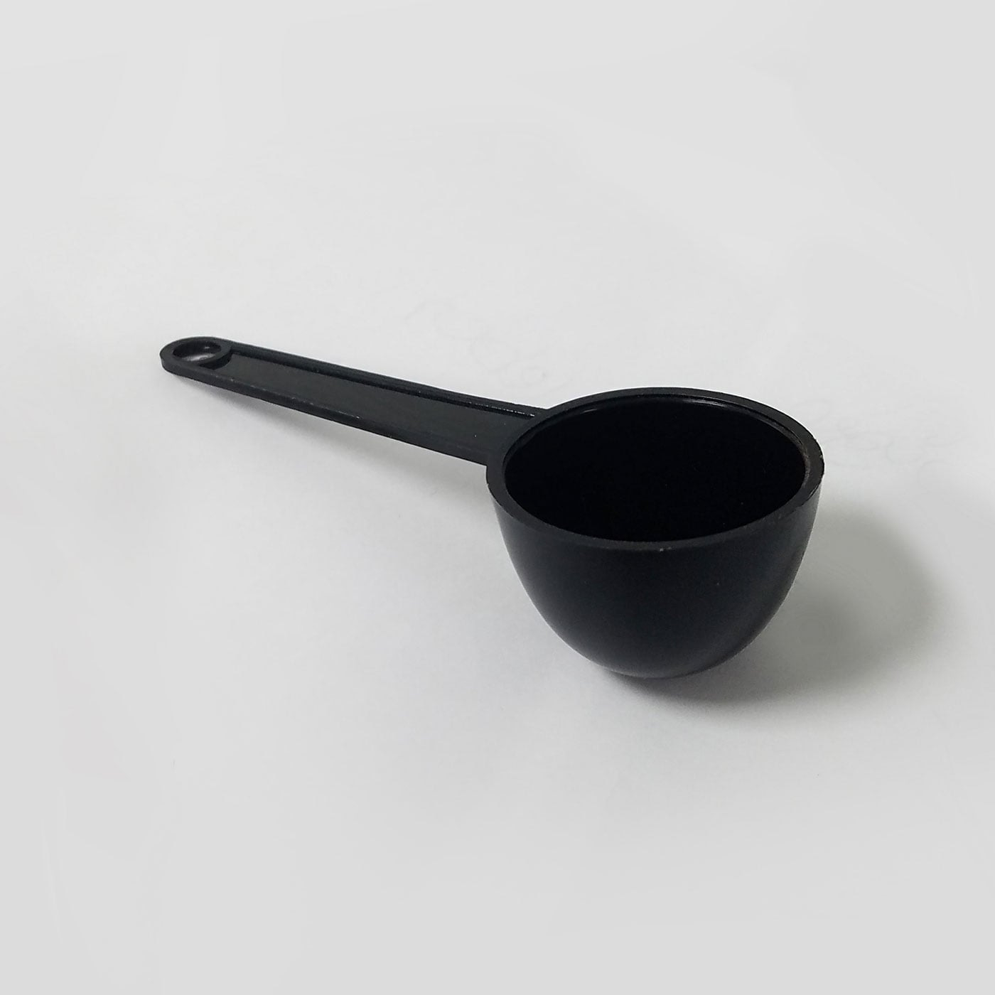 Black measuring spoon on white background, close-up, isolated