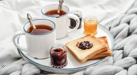 Frühstück im Bett: Toast mit Marmelade, Tee und Decke