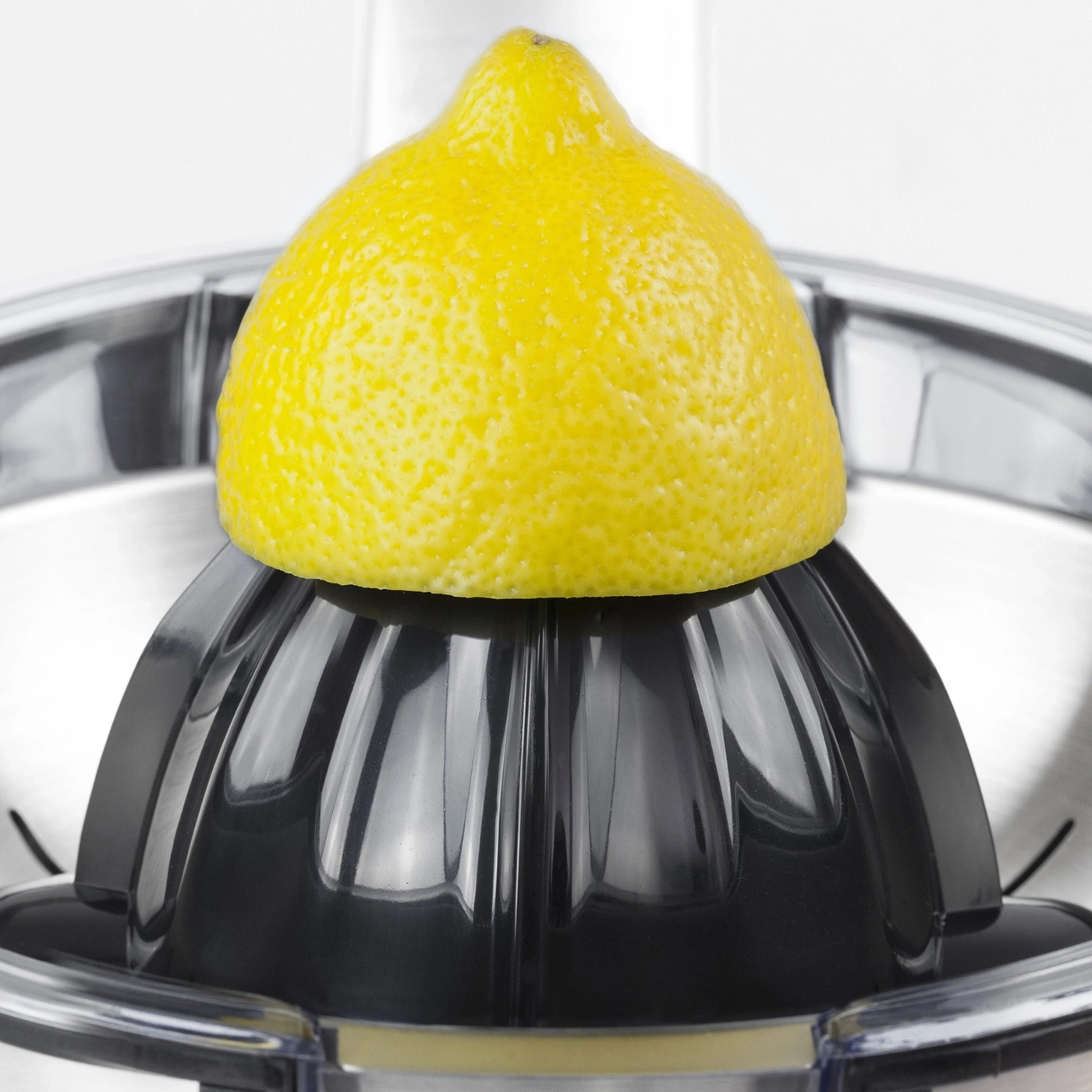 Lemon on a lemon squeezer. Yellow fruit, black plastic, stainless steel.