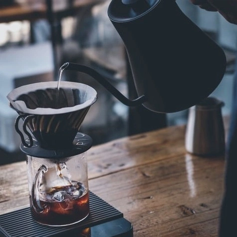 Pouring water into coffee filter. Brewing coffee. Coffee preparation process.