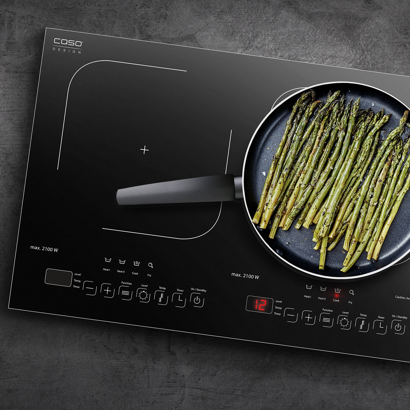 Black induction cooktop with asparagus in pan, control panel with buttons and display.