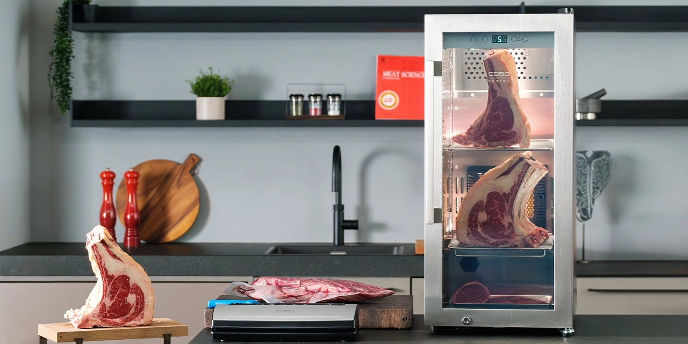 Reifeschrank mit zwei großen Steaks und einem Vakuumierer daneben.