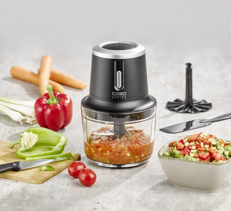 Food processor with vegetables and ingredients for a dish on a table