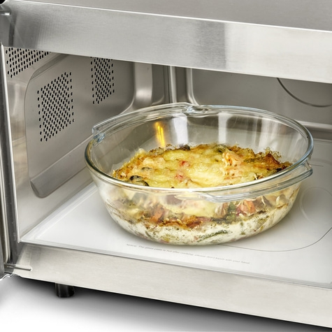 Casserole in a glass bowl inside a microwave. Food being heated up.