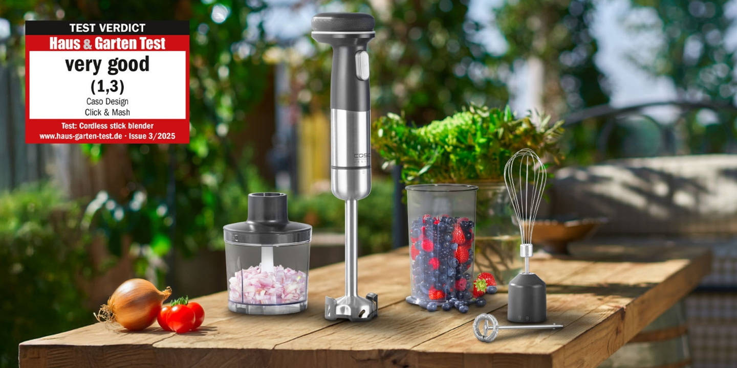 A stick blender with accessories on a wooden table outdoors, rated very good.