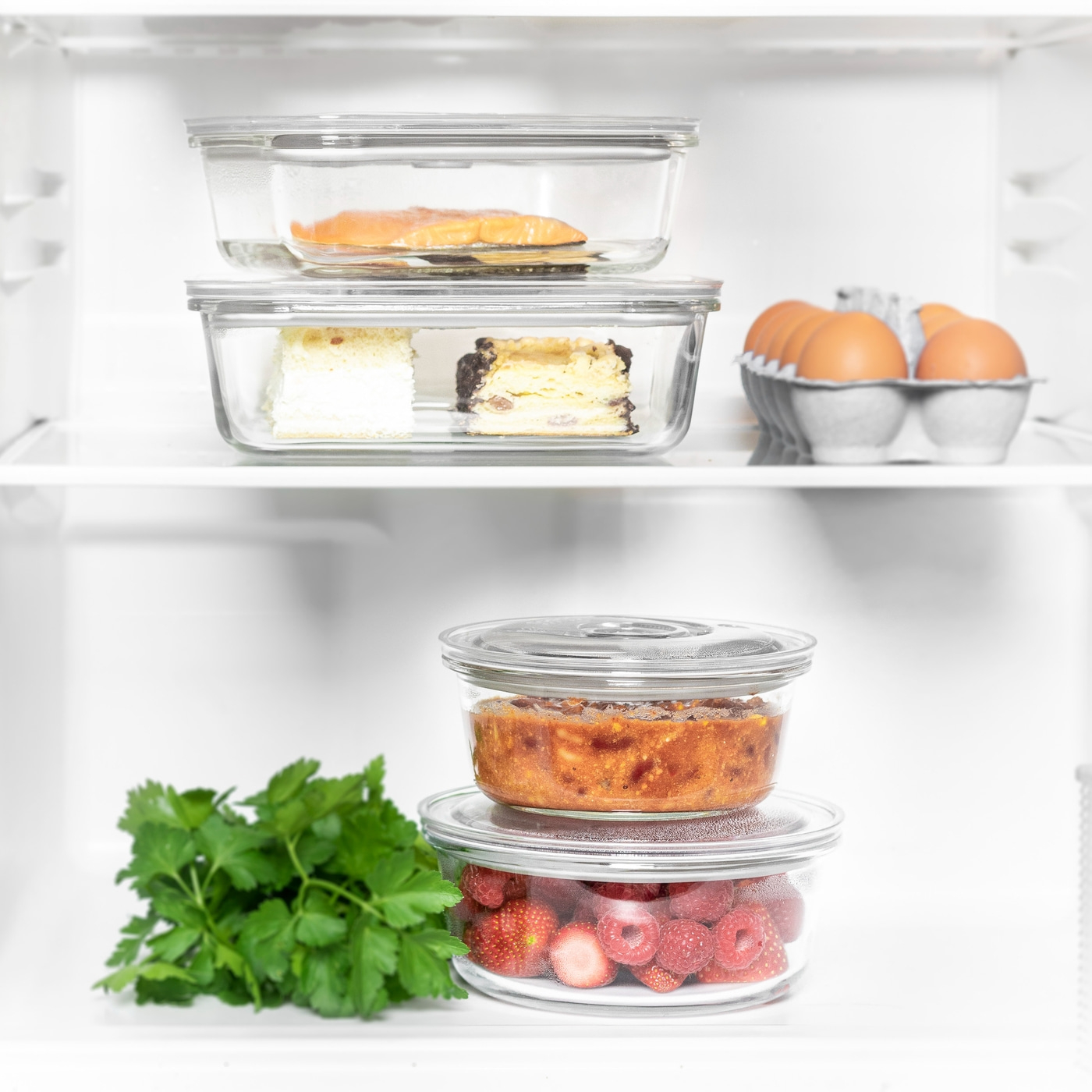 Refrigerator with food: salmon, cake, eggs, casserole, berries, and parsley.