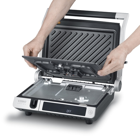 Person opens an electric contact grill to clean the grill plates.
