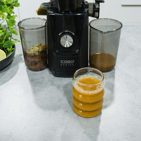 fertiger Karottensaft mit Melone & co aus dem Juice Fit. Trester und Gerät im Hintergrund.