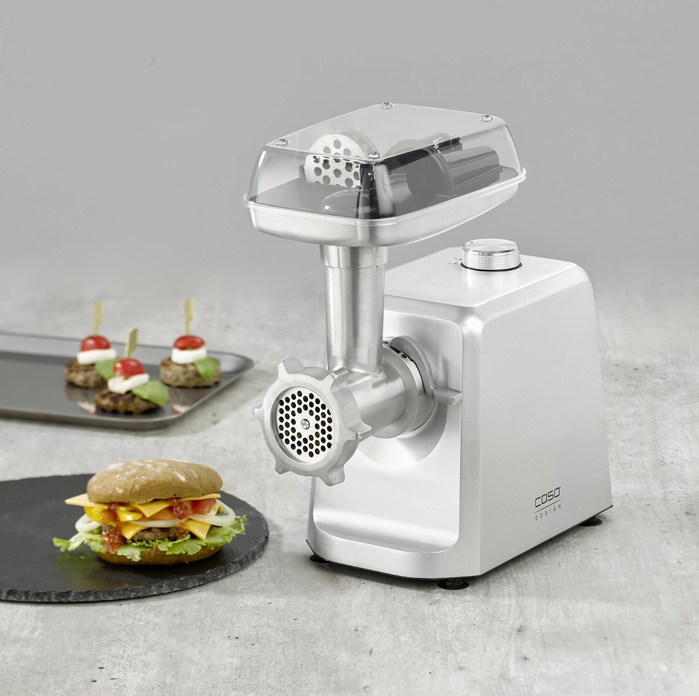 Fleischwolf mit Burger und Häppchen auf einem Tisch