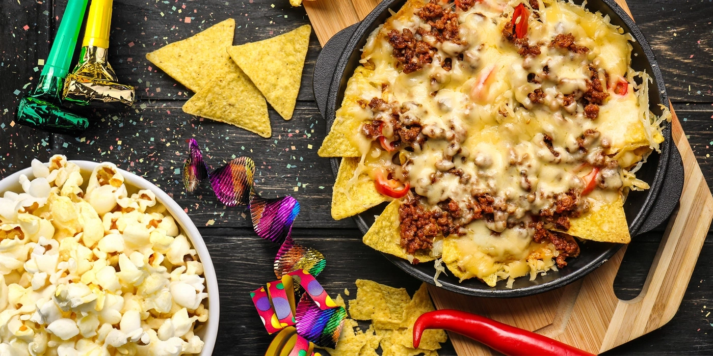 Partytisch mit Nachos, Popcorn, Partydekoration und roter Chili
