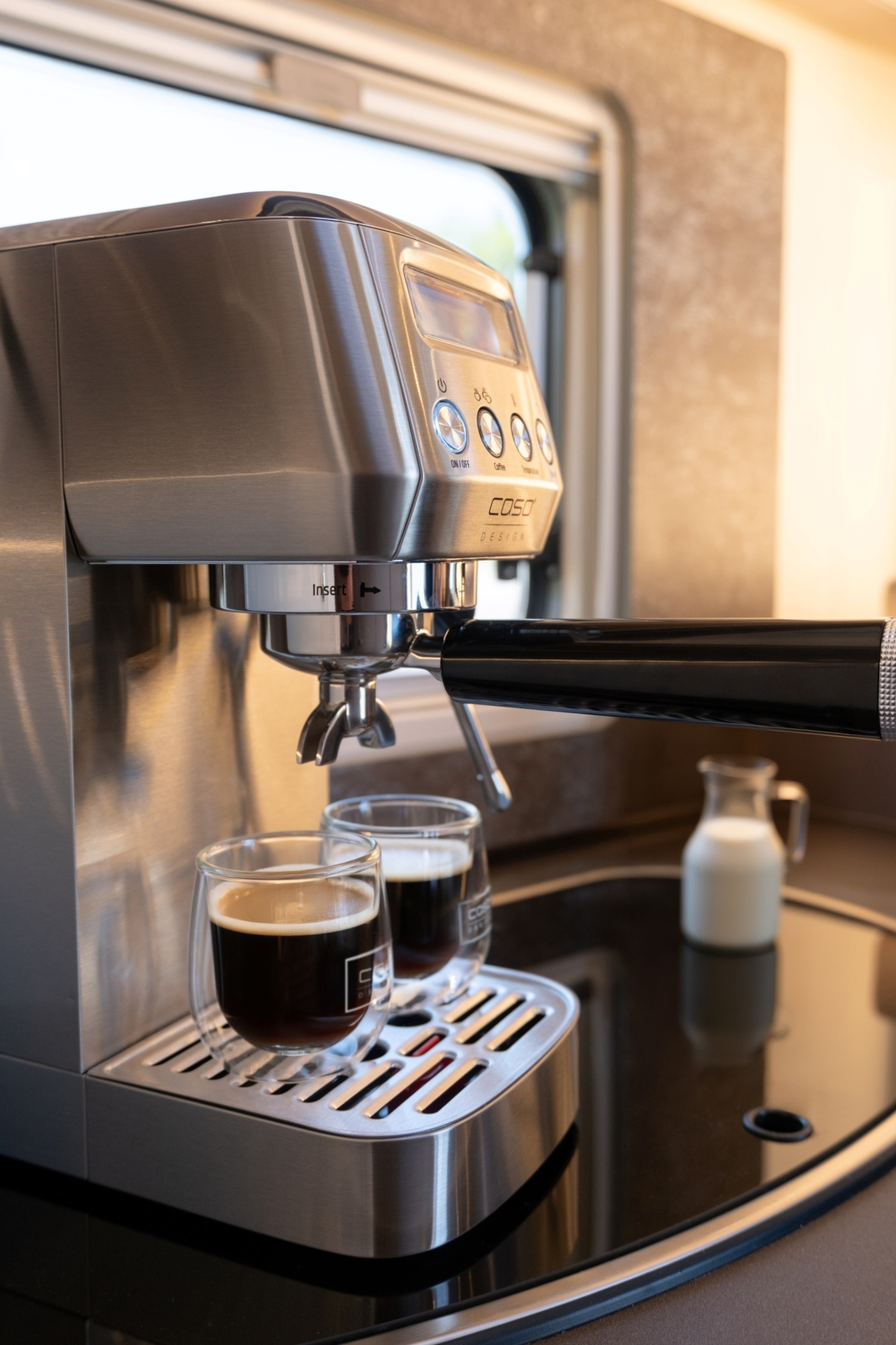 Eine silberne Espressomaschine mit zwei Gläsern Kaffee.