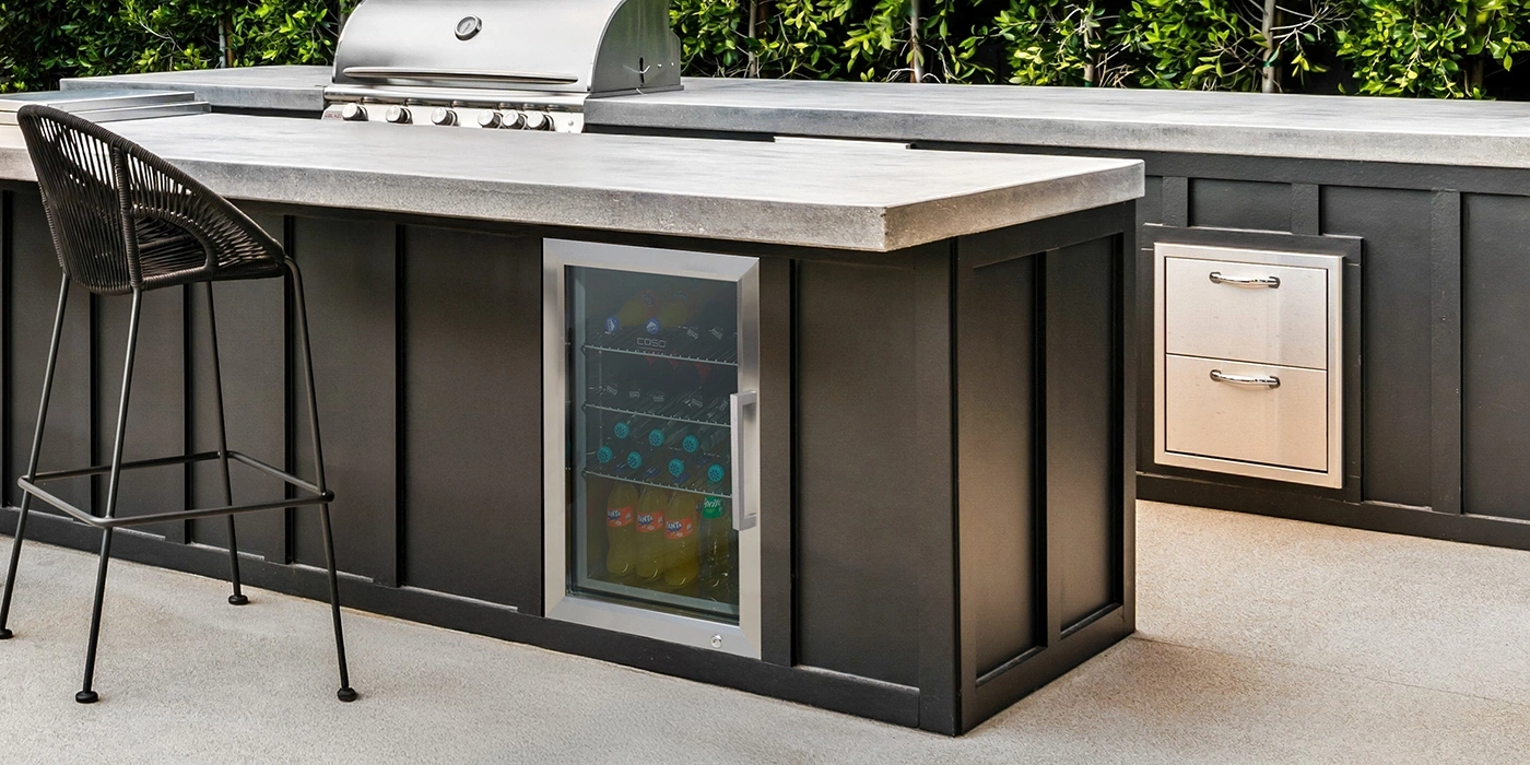 Moderne Outdoor-Küche mit Grill, Kühlschrank und Barhocker. Schwarze Schränke.