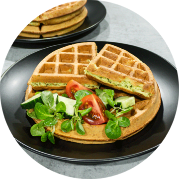 Waffles with salad and tomatoes on a black plate, delicious food