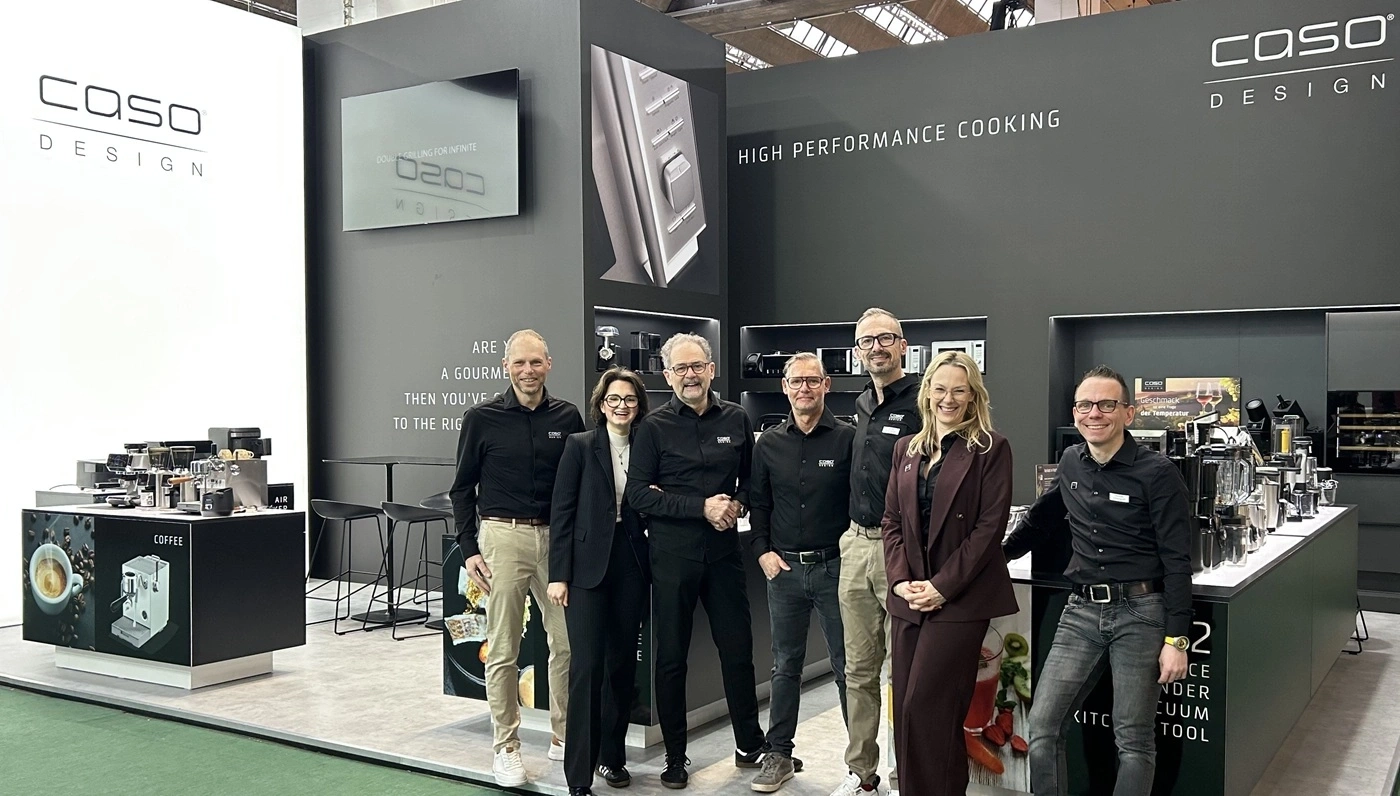Teamfoto vor einem Messestand mit Küchengeräten und dem Schriftzug Caso Design.