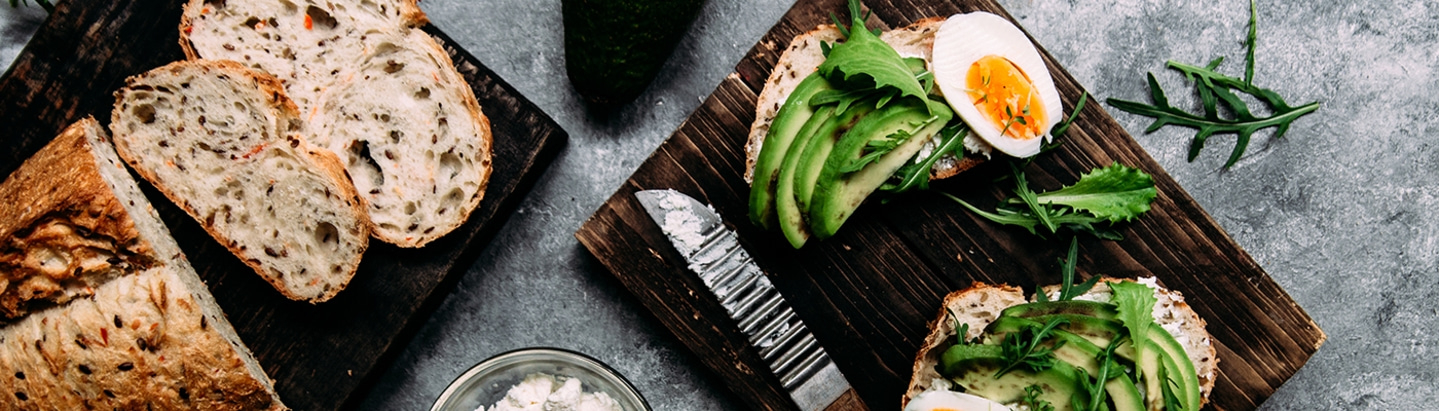 Avocado-Toast mit Ei und Brot auf Holzbrett, Nahaufnahme, Essen