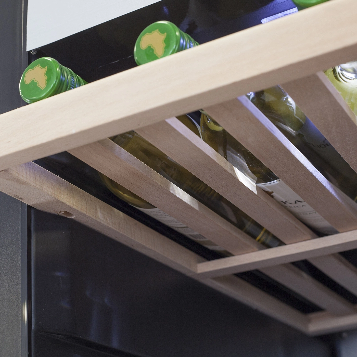 Close-up of wine bottles on a wooden shelf inside a cooler.