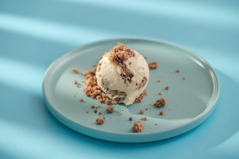 Eiscreme mit Streuseln auf einem Teller vor blauem Hintergrund
