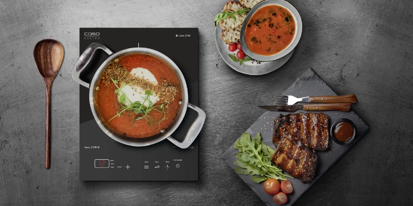 Köstliches Essen: Suppe, Rippchen, Kochplatte, Löffel, Brot, Tomaten, Kräuter, Soße