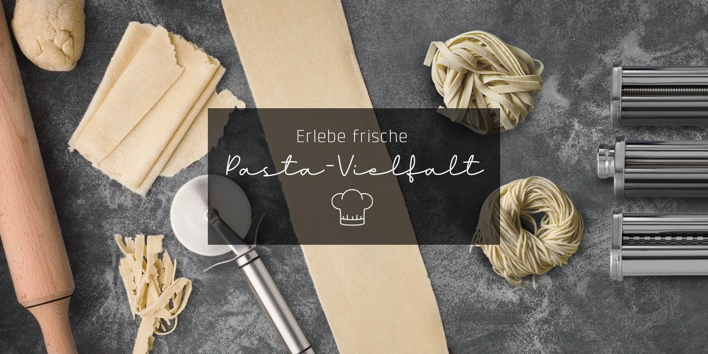 Frische Pasta-Vielfalt mit Nudeln, Nudelmaschine und Zutaten auf grauem Hintergrund.