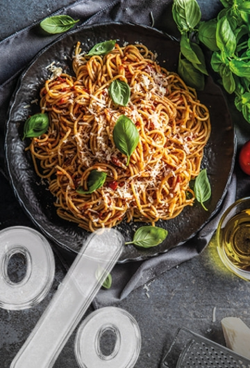 A close-up of spaghetti with tomato sauce and basil on a dark plate with transparent percentage signs in the foreground.